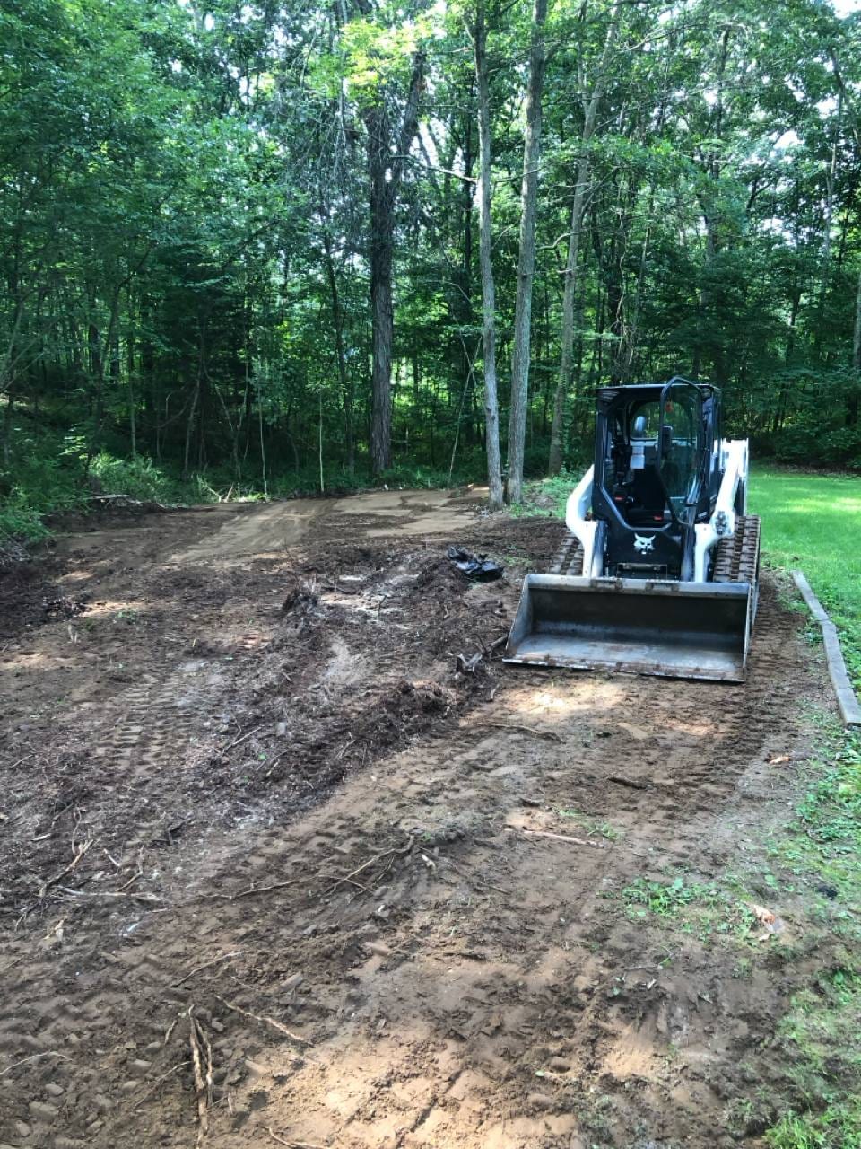 Skid-steer grading and clearing a backyard area
