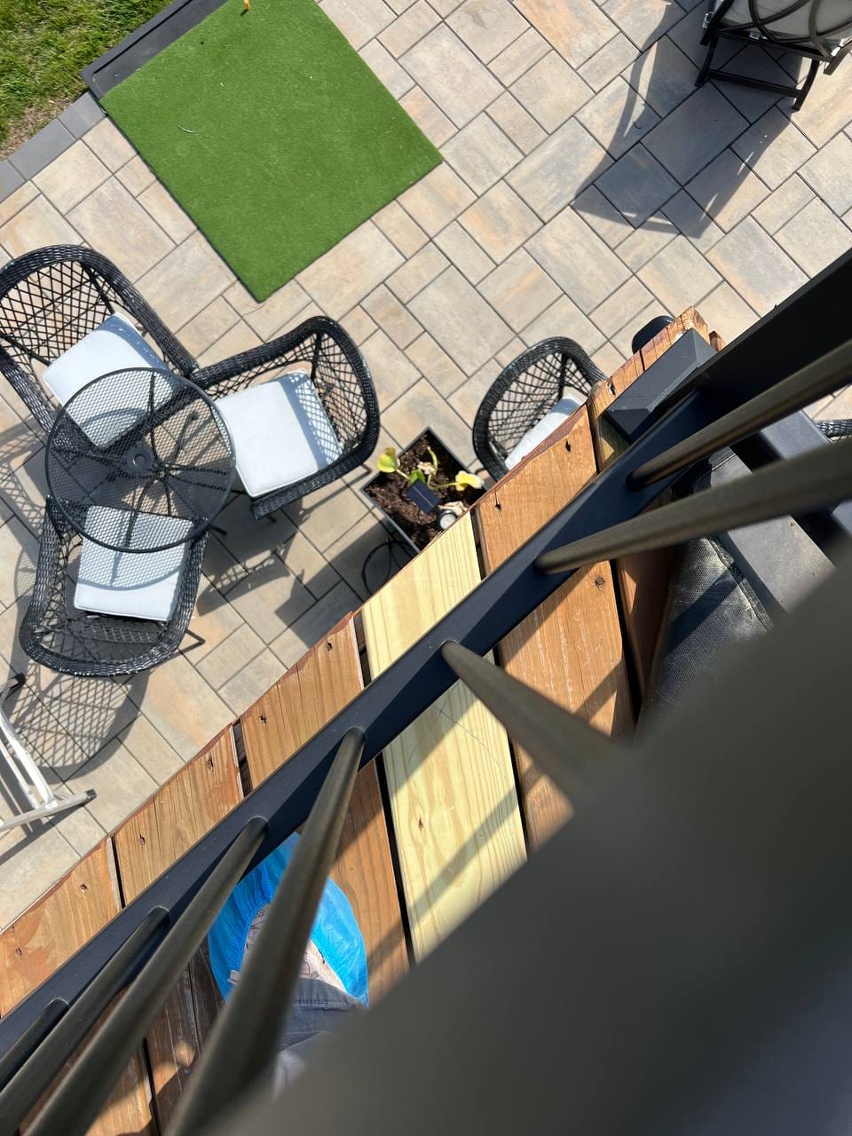 Paver patio with turf and a deck above